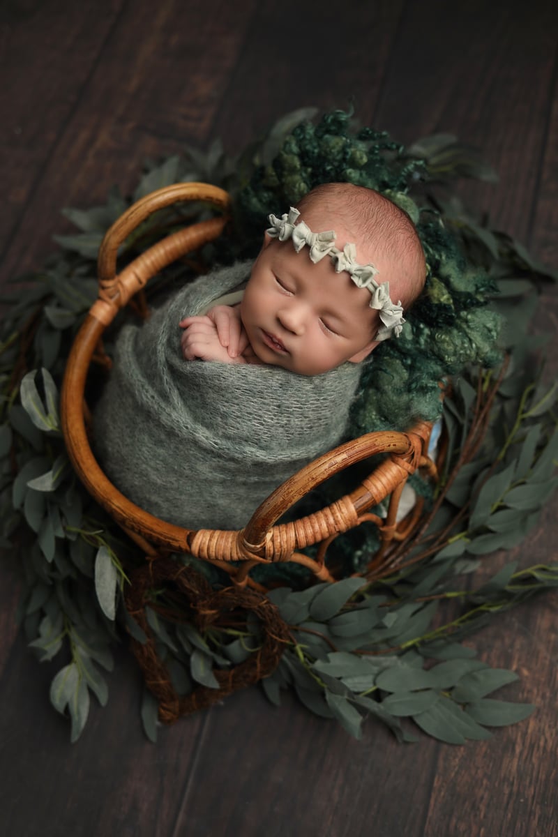 baby in basket with greenery and bows around her head