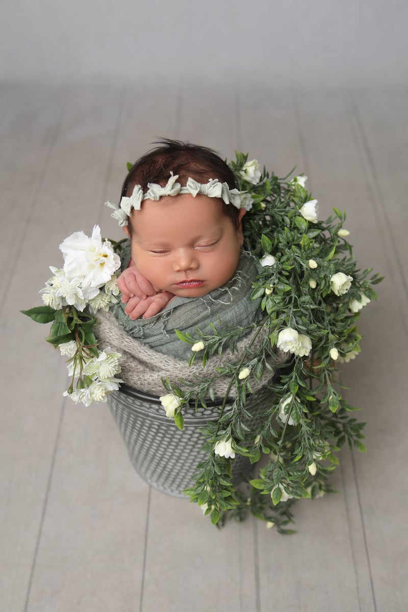 baby posing with small flowers in a basket