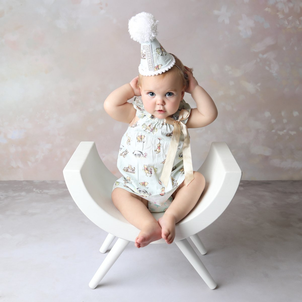 baby wearing a cute hat sitting on a chair for a photoshoot