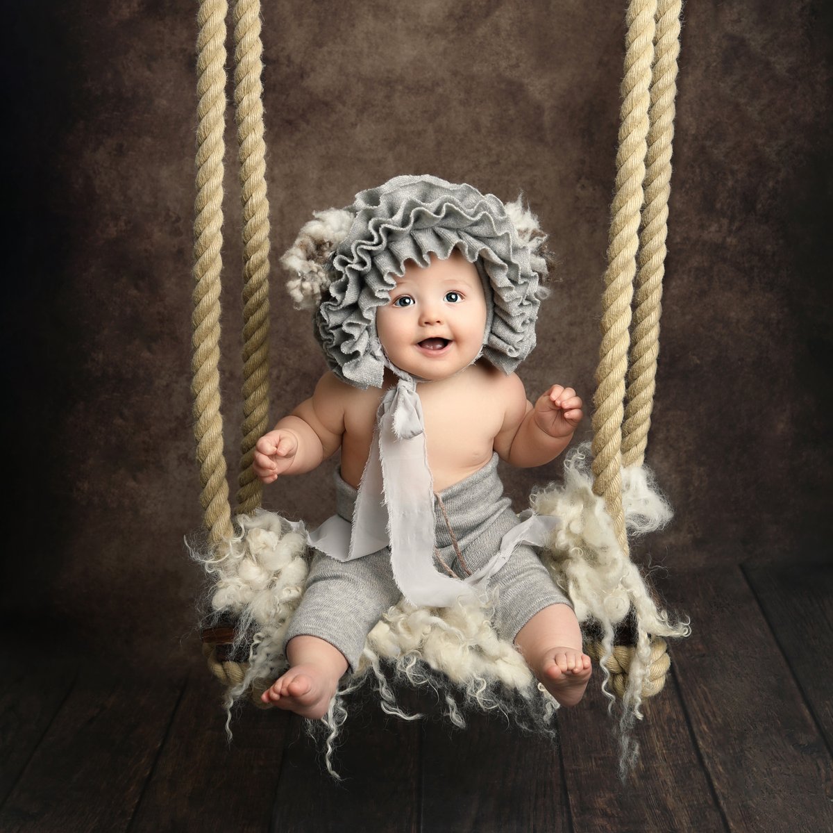 smiling baby on a swing posing for a professionally taken photograph