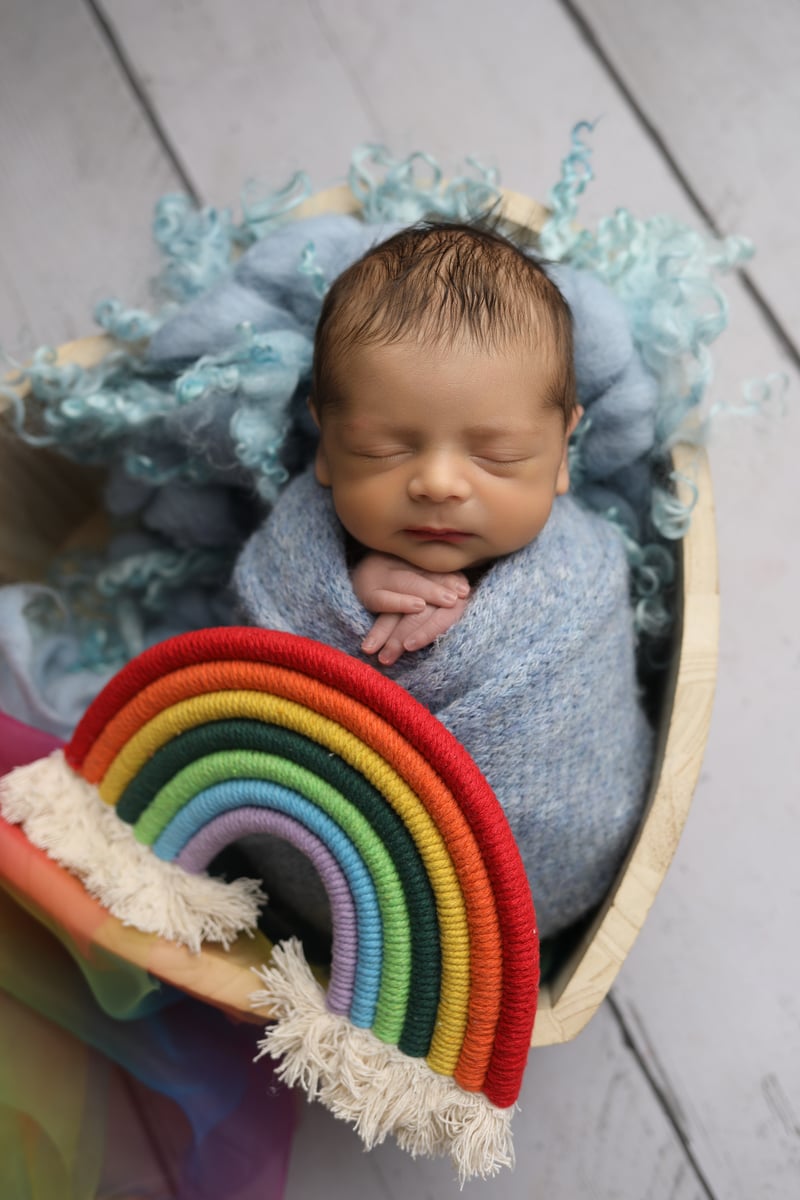 baby wrapped up in basket with soft rainbow 