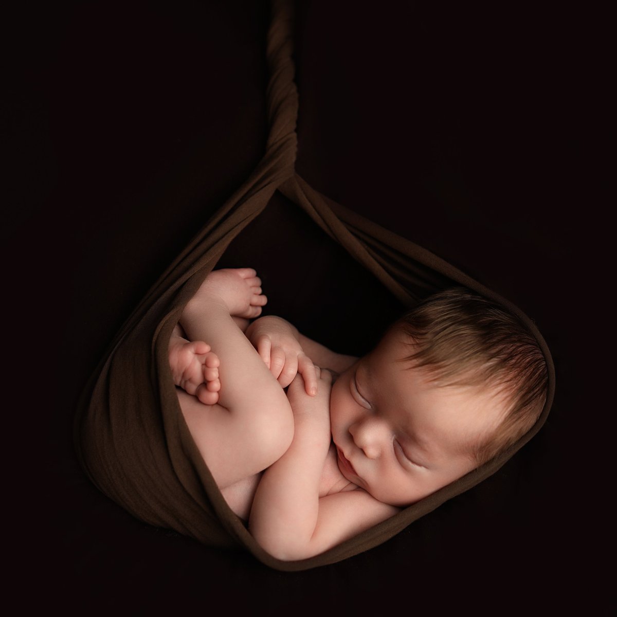 baby sleeping in brown fabric for a high quality baby art studios photo