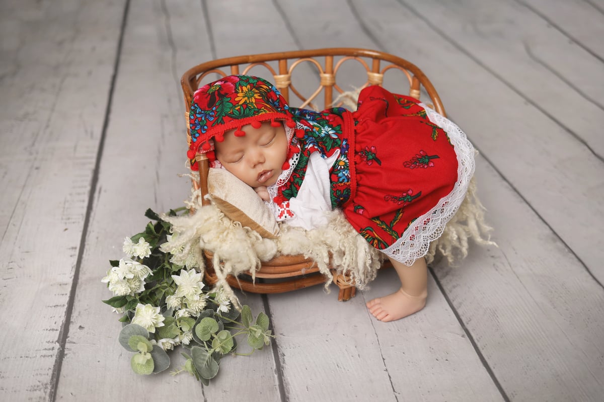 sleeping baby in a basket with a cute dress on