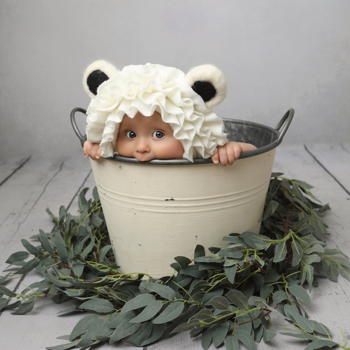baby in a bucket with bear ears posing for a professional photoshoot