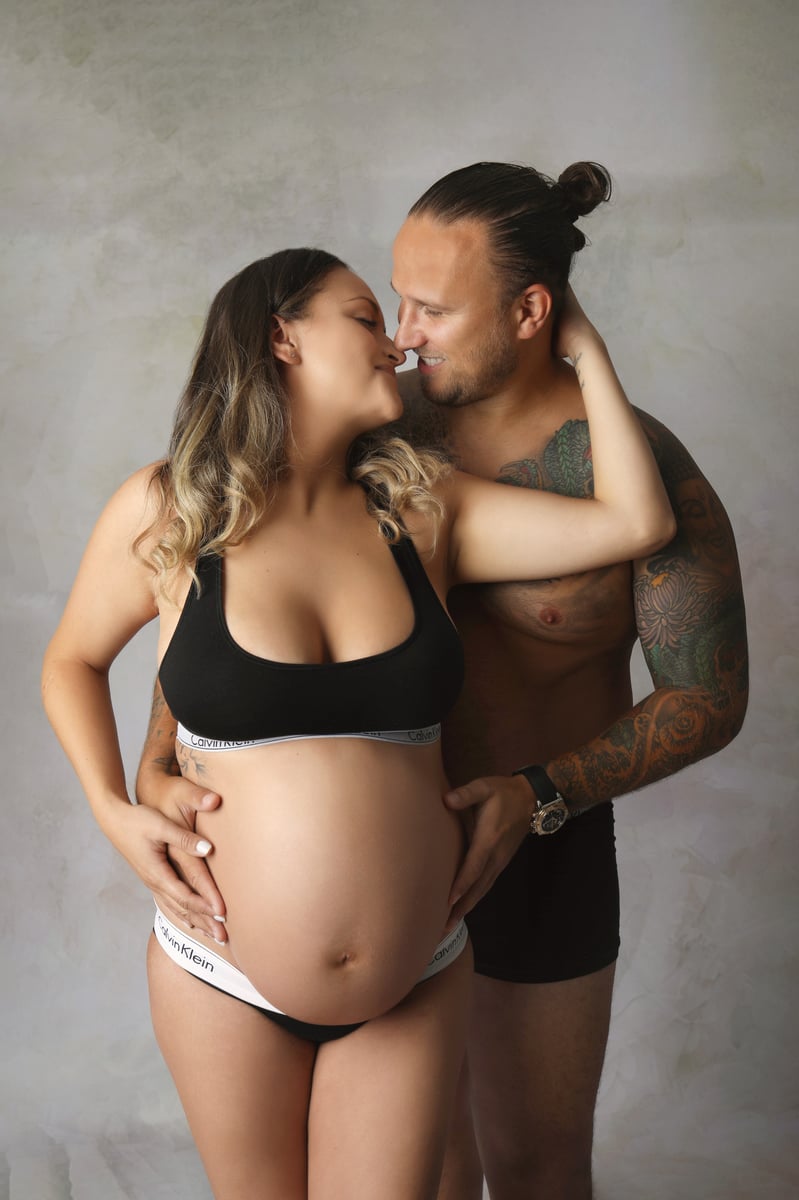 mother and father posing for a photoshoot with baby bump