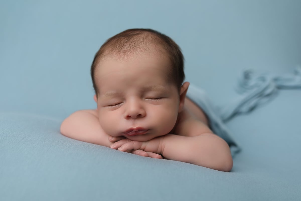 baby sleeping on a blue background for a professionally taken photo