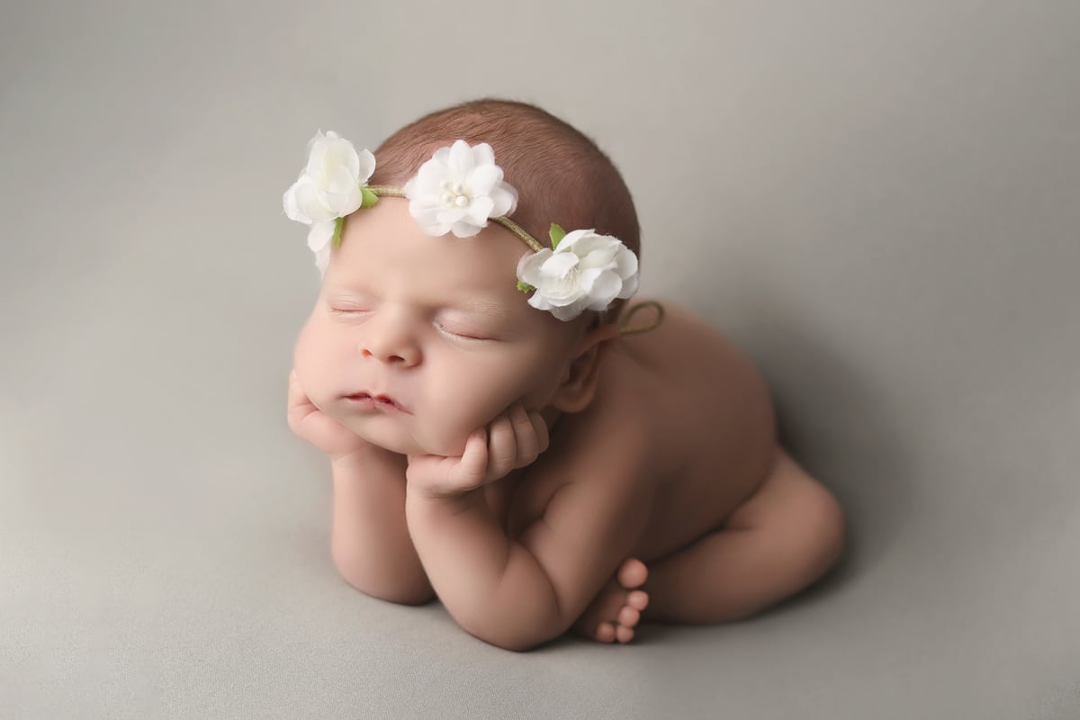 baby with flowers around her head posing for a photo