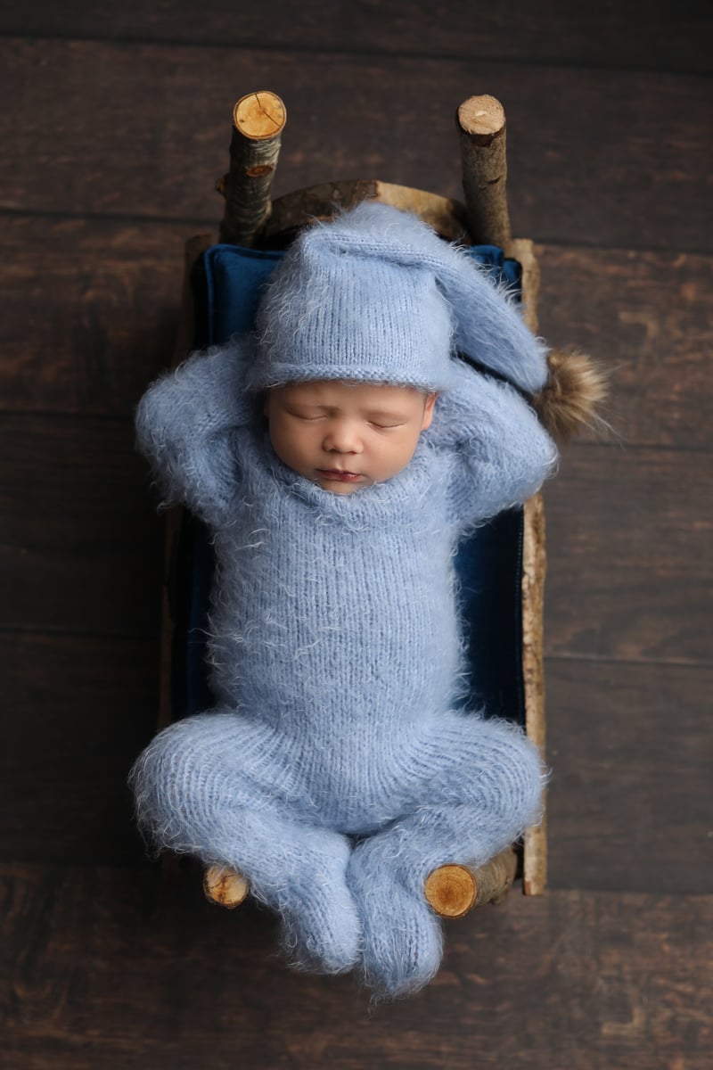 baby relaxing in a small wooden cot
