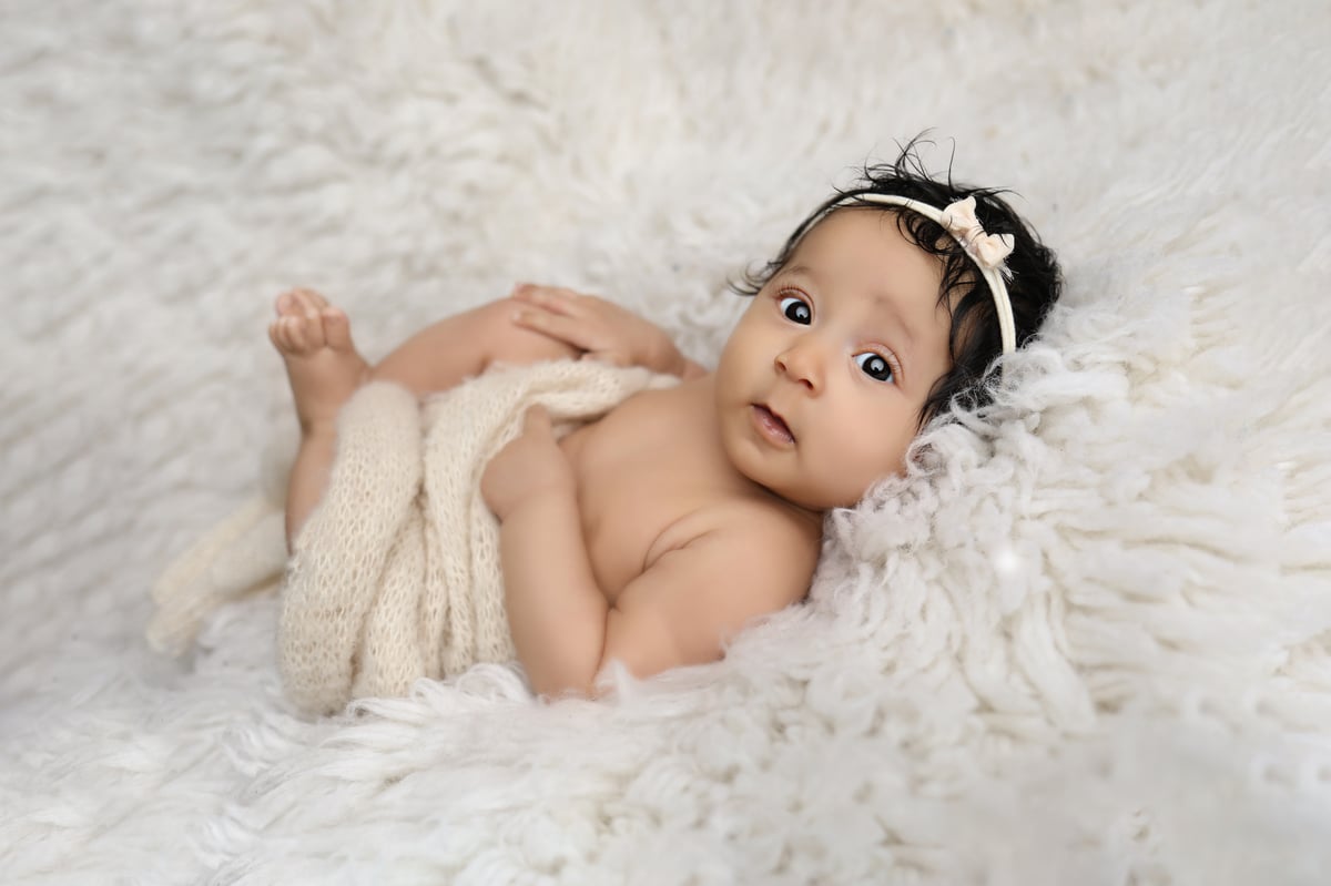 baby posing during a photoshoot on a soft blanket