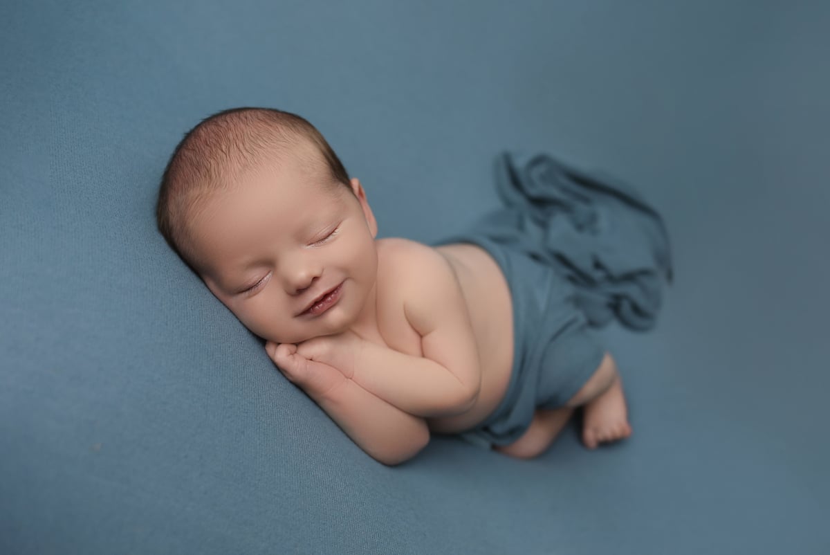 baby sleeping on a grey background looking happy