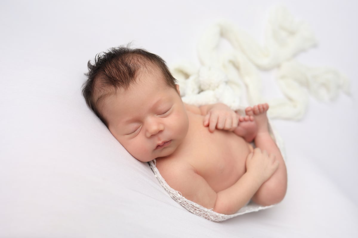 baby sleeping in professional photoshoot on a soft pink background